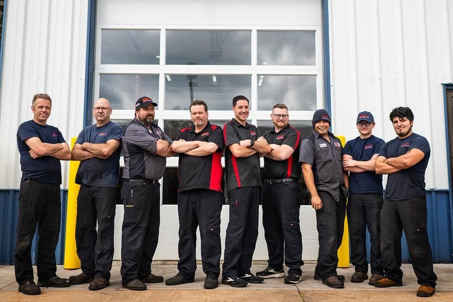 A group of men are posing for a picture in front of a garage door.