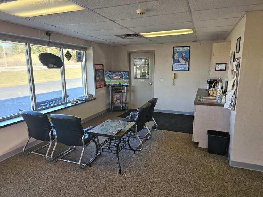 A waiting room with chairs , a table and a television.