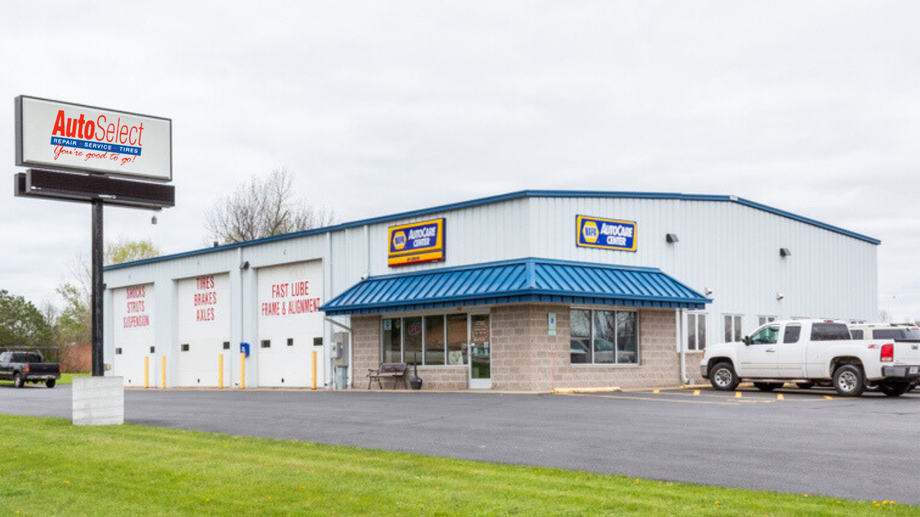 A white truck is parked in front of an auto shop.