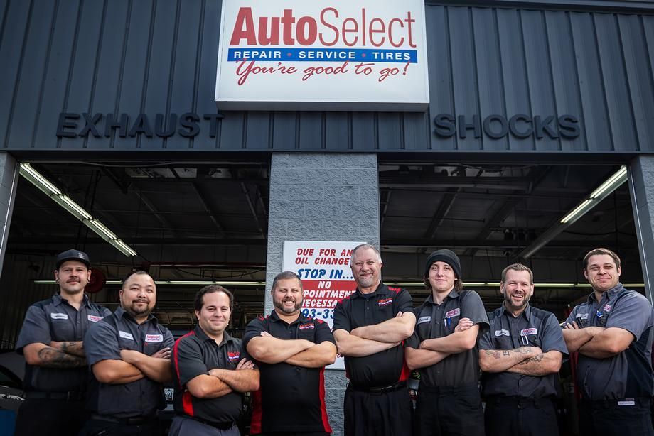 A group of men are posing for a picture in front of a garage.