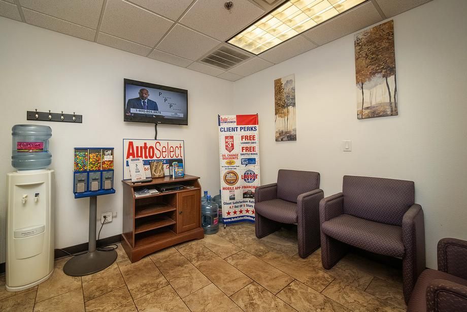 A waiting room with chairs , a tv and a water cooler.