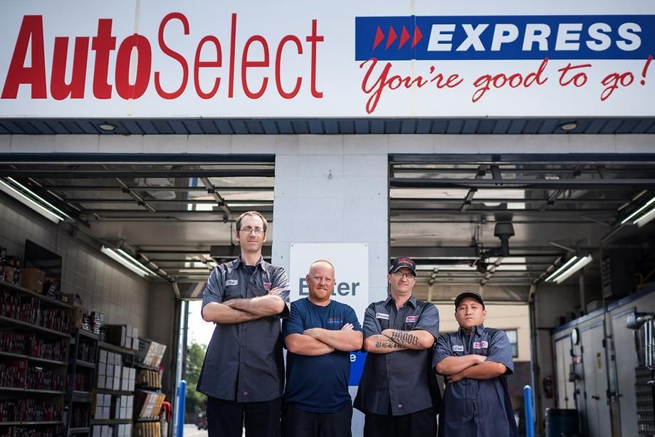 A group of men are standing in front of an autoselect express sign.
