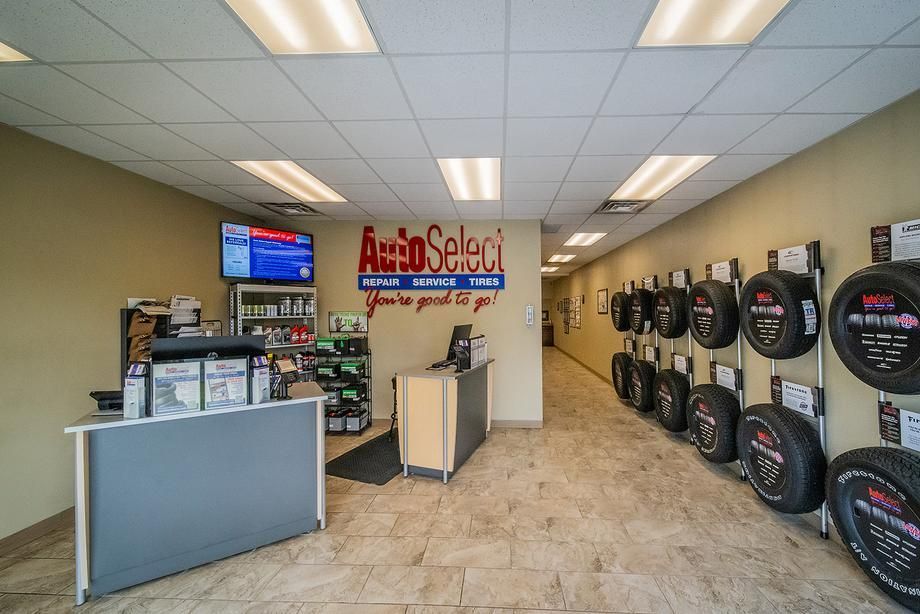 The inside of an auto select tire store with tires hanging on the wall.