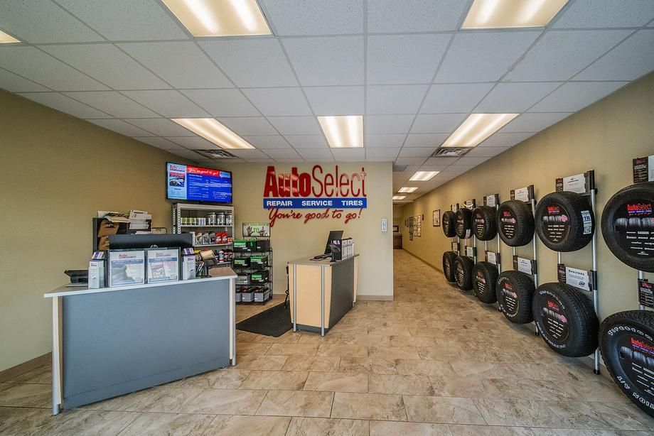 The inside of an auto select tire store with tires hanging on the wall.