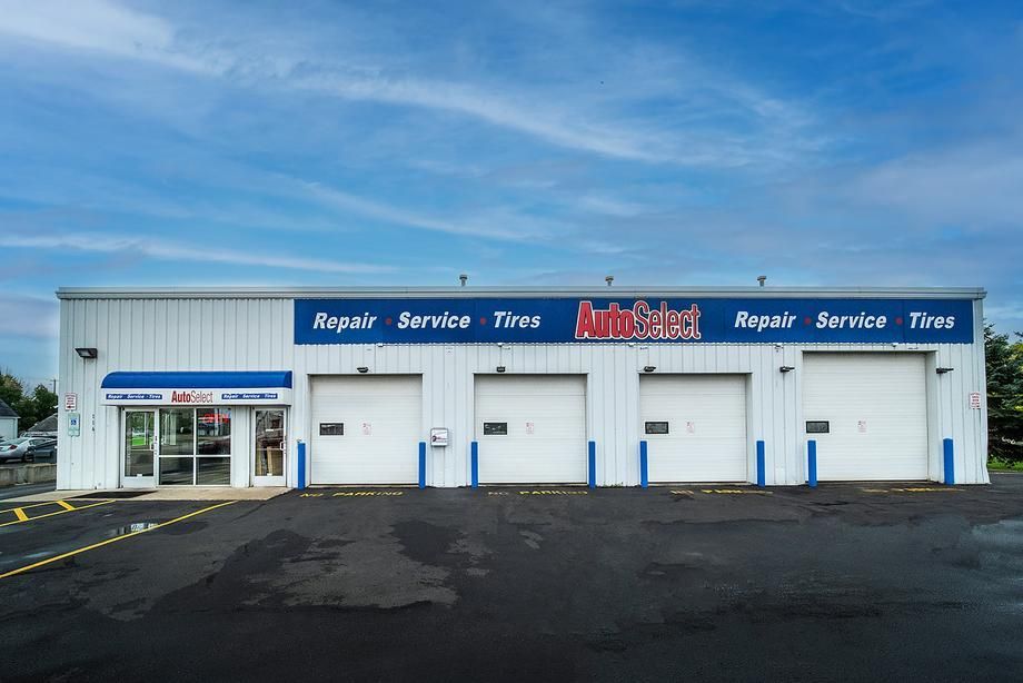 A white building with a blue sign that says repair service tires