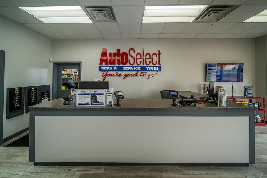 The front desk of an auto select store with a sign on the wall.