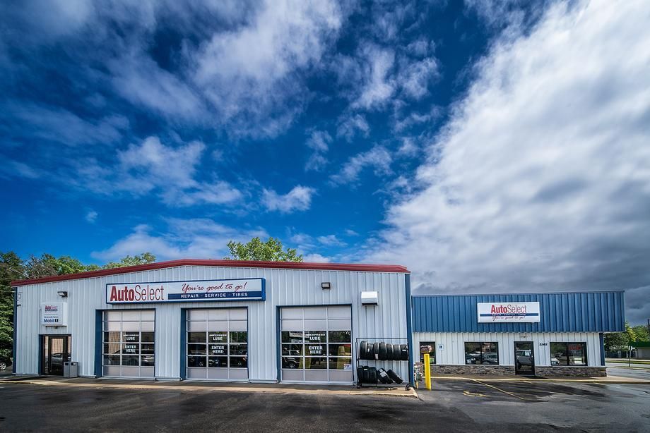 A large white building with a blue roof is a tire shop.