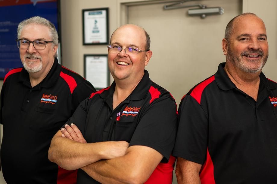 Three men are standing next to each other with their arms crossed and smiling.