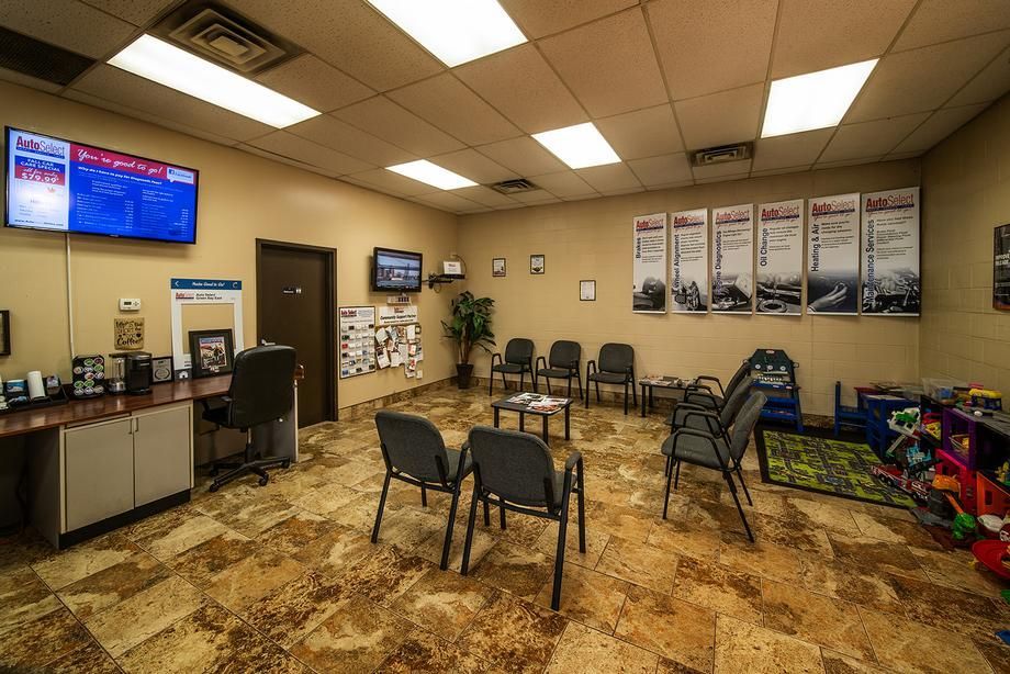 A waiting room with chairs , a desk and a television.