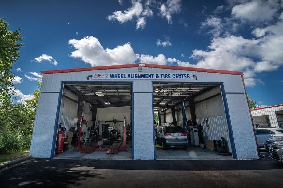 A car is parked in a garage at a wheel alignment and tire center.