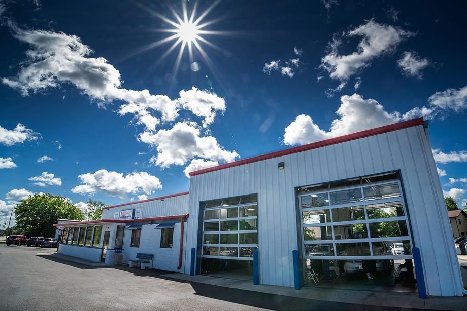 The sun is shining brightly on a white building with a red roof.