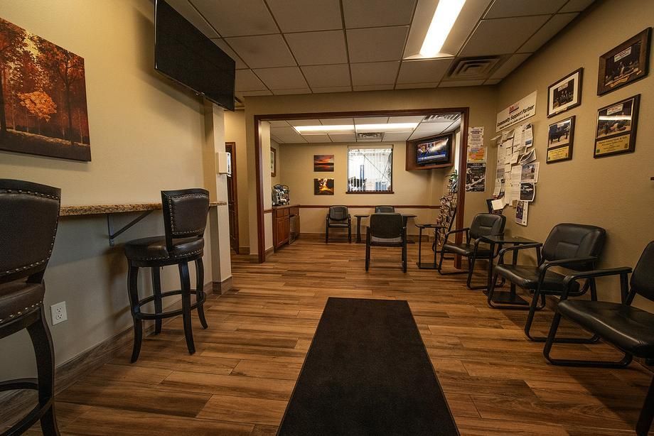 A waiting room with chairs , tables and a television.
