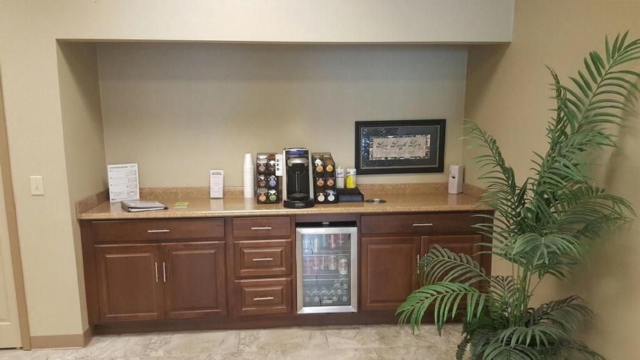 A kitchen with wooden cabinets , a refrigerator , a coffee maker , and a plant.
