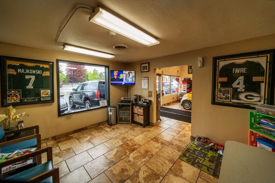 A waiting room with chairs , a television , and framed jerseys on the wall.