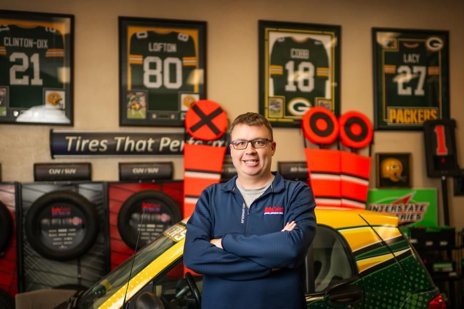 A man is standing in front of a green bay packers car