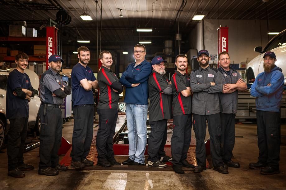 A group of mechanics are posing for a picture in a garage.