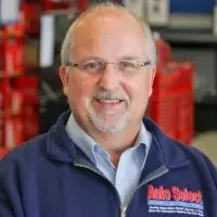 A man with a beard and glasses is wearing a blue jacket and smiling.