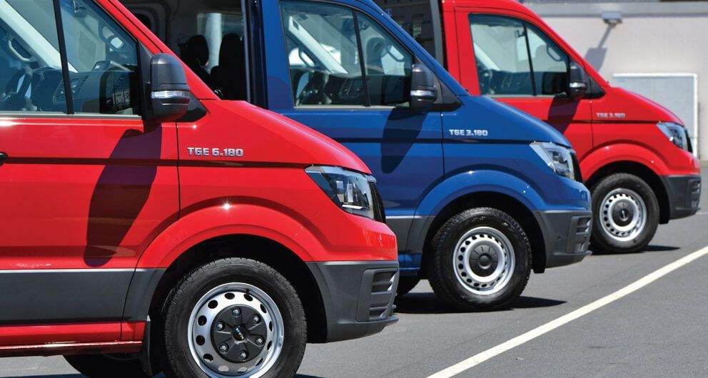 A row of red and blue vans are parked in a parking lot.