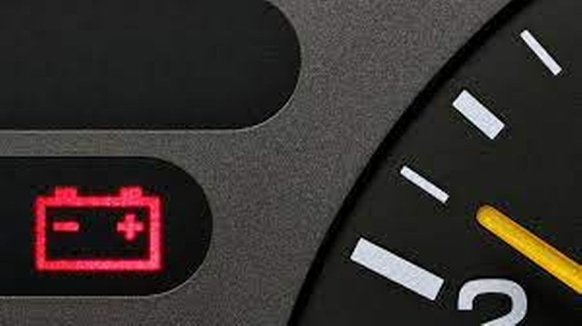 A close up of a car dashboard with a red battery warning light.