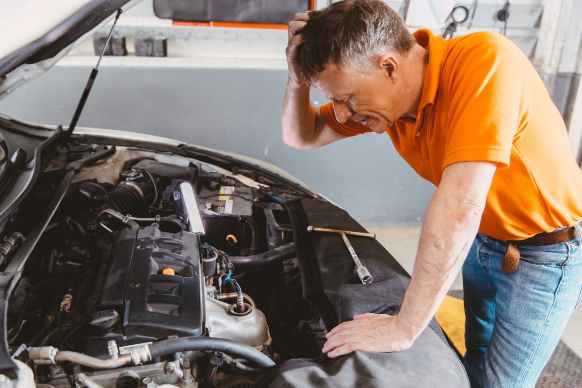 A man is looking under the hood of a car.