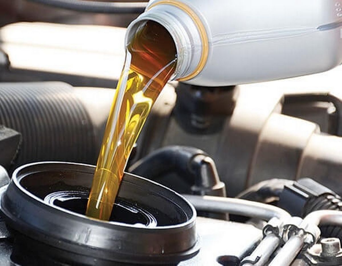 A bottle of oil is being poured into a car engine