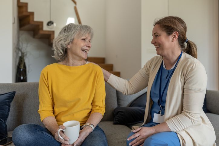 A nurse conducts an interview with a patient at home in a happy mood over coffee.