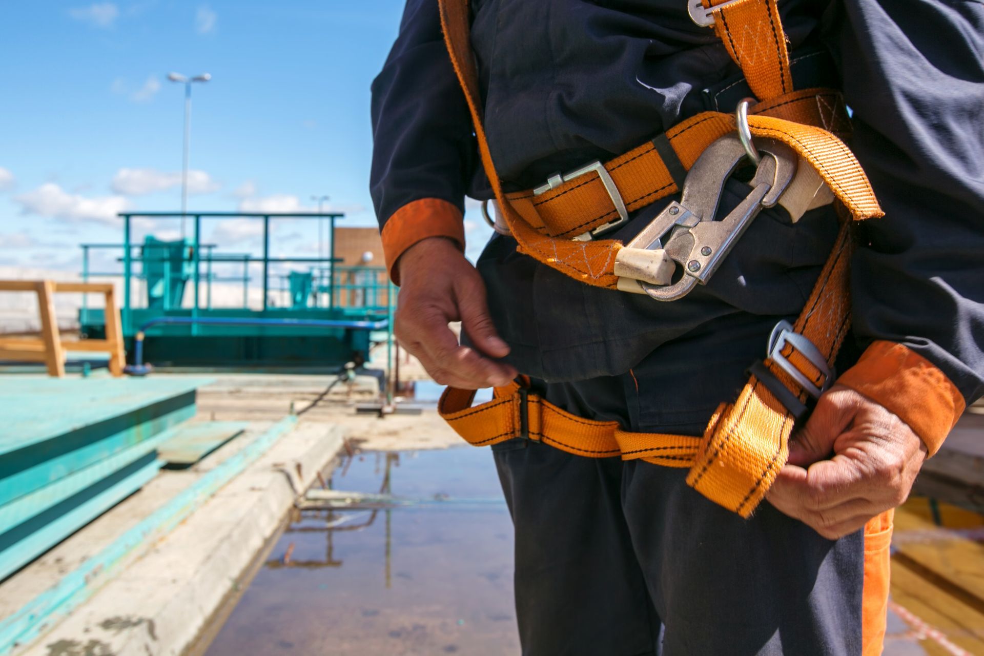 A man is wearing a safety harness on a construction site.