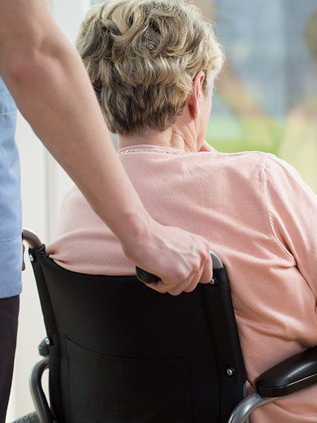 Persona su sedia a rotelle spinta da un assistente.