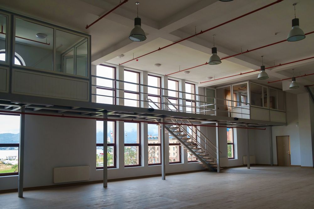 Un trabajador del muelle dirige una grúa amarilla y azul que levanta metal. Cielo azul y costa.