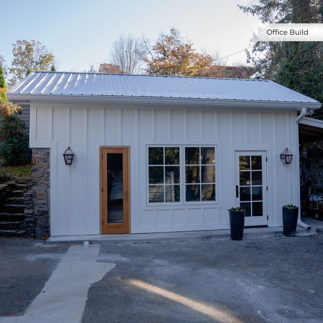 Small white storefront with a wood-framed door, large front window, and two wall lanterns