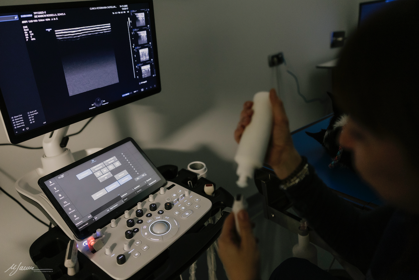 Lungo corridoio con porte bianche e attrezzature mediche in fondo.