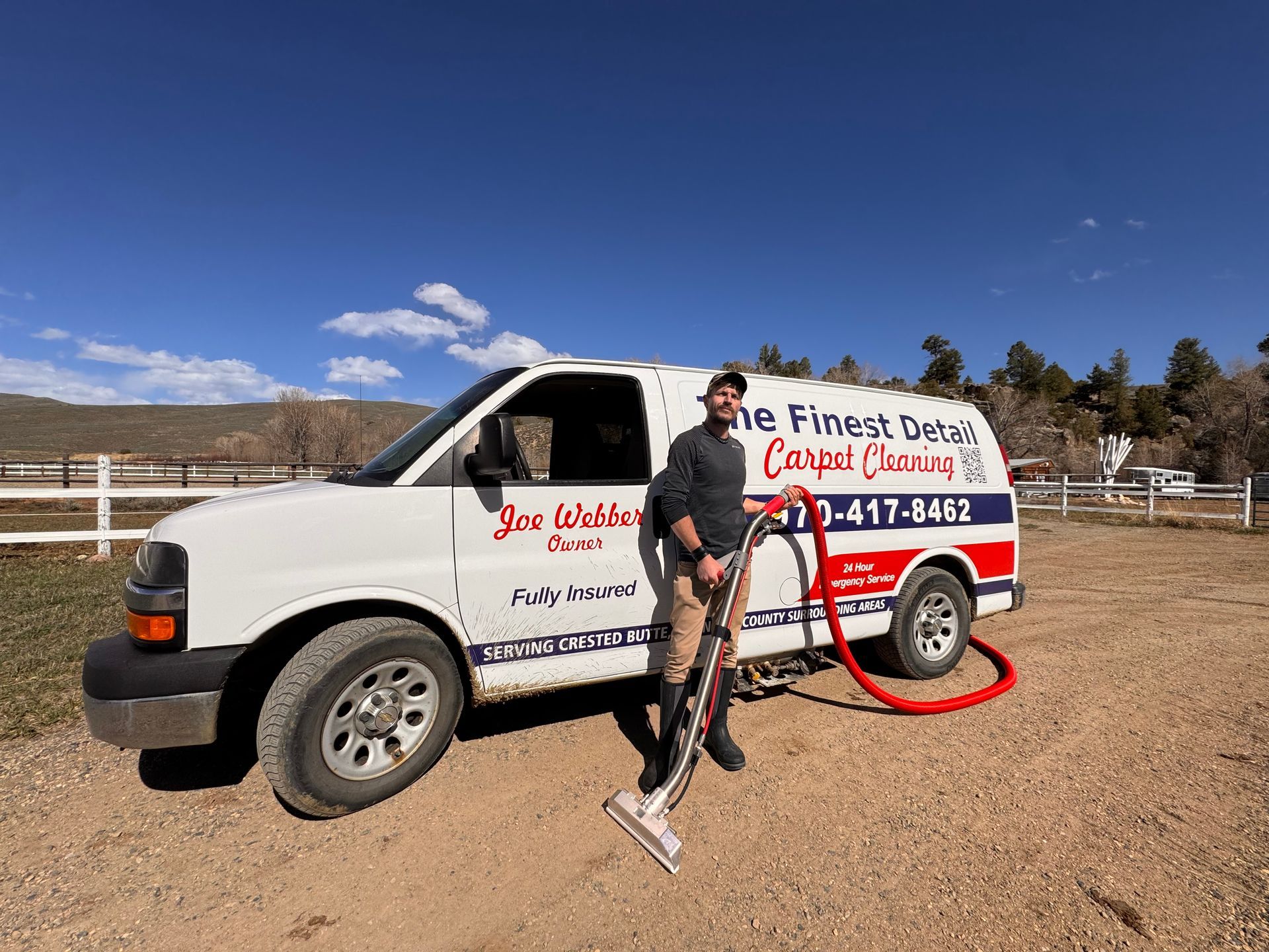 A man is standing in front of a van with a vacuum cleaner attached to it.