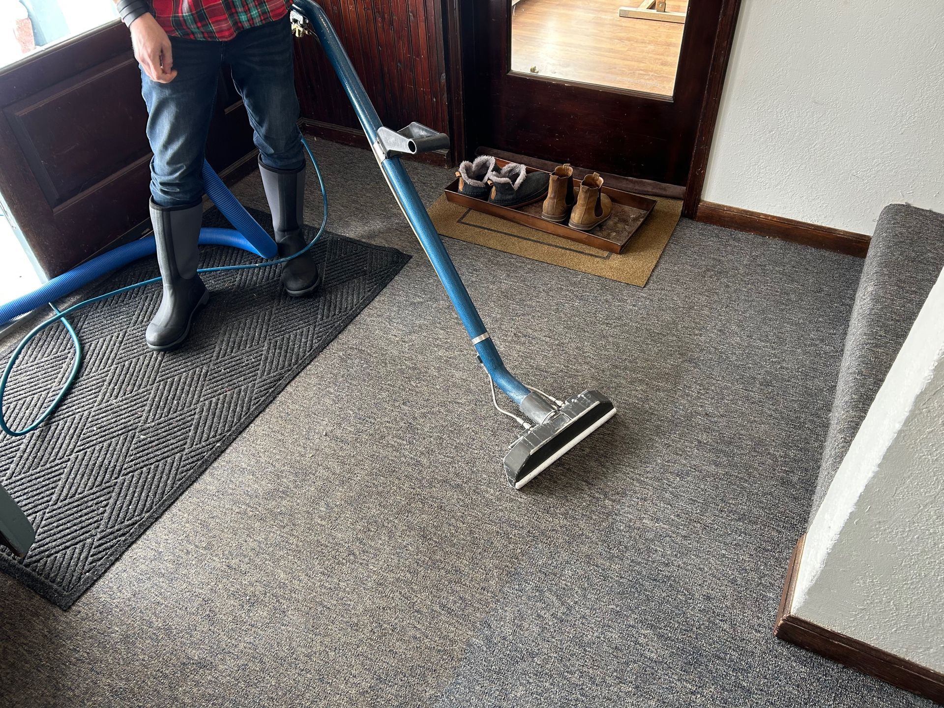 A person is cleaning a carpet with a vacuum cleaner.