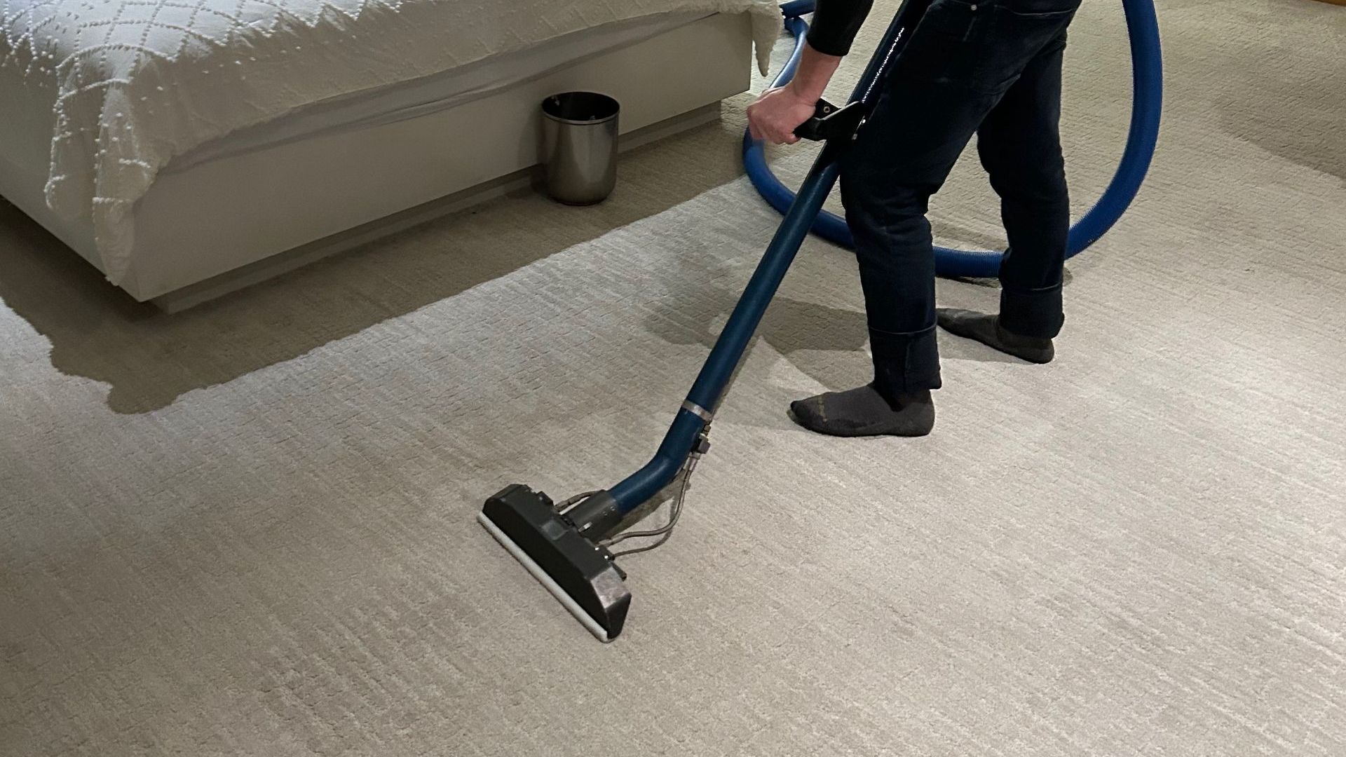 A man is using a vacuum cleaner to clean a carpet.