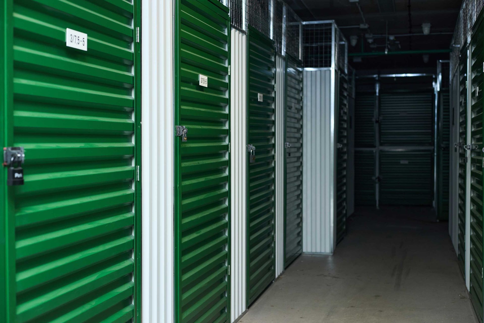 Rows of green storage unit doors inside a facility.