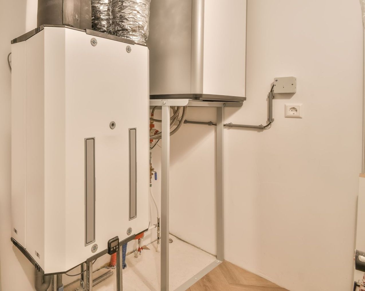 Une chaudière à gaz blanche et un chauffe-eau dans une buanderie.