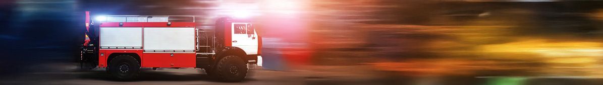 Fire truck with flashing lights speeding forward at night.