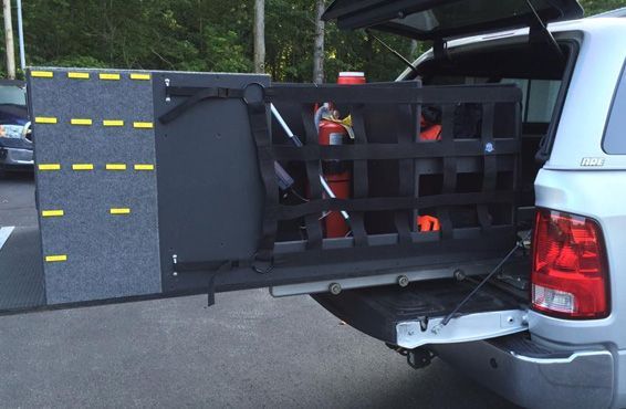 Open rear of a truck with a cargo organization system, holding emergency equipment.