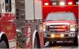 Fire truck and ambulance with flashing lights on a road.