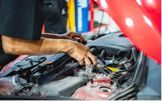 Mechanic with gloved hands working on a car engine. Red car, garage setting.