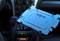 Interior of a vehicle with a mounted Havis tablet holder, dashboard, and radio equipment visible.