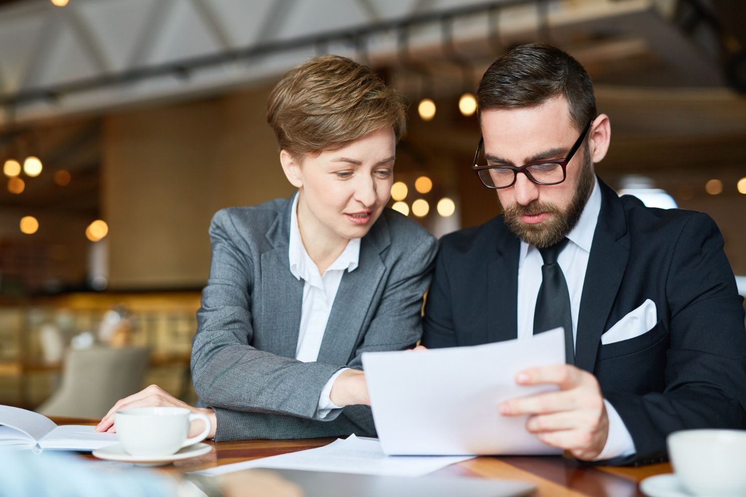 Two business professionals reviewing documents together at a cafe table
