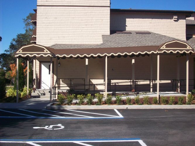 A brown awning covers a building entrance with a handicap parking space in front.
