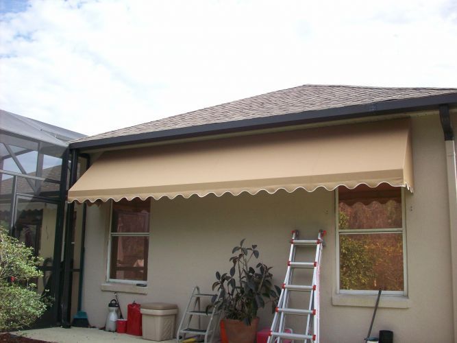 Beige awning over windows on a light brown building; a ladder leans against the wall.