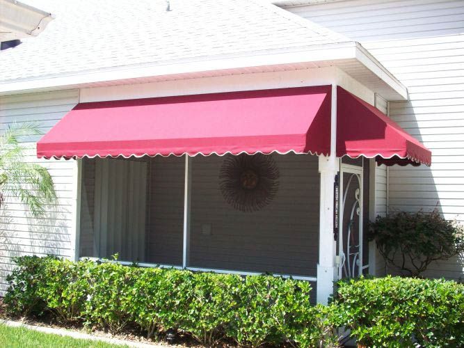 Red awning over a screened porch of a white house with bushes in front.