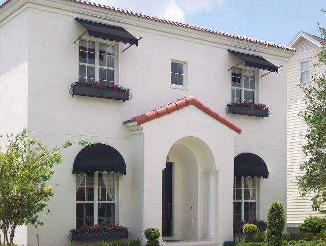 White stucco house with black awnings, flower boxes, and red tile roof.