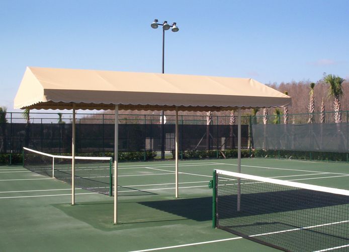 Tan awning over a tennis court, with green court and net visible.