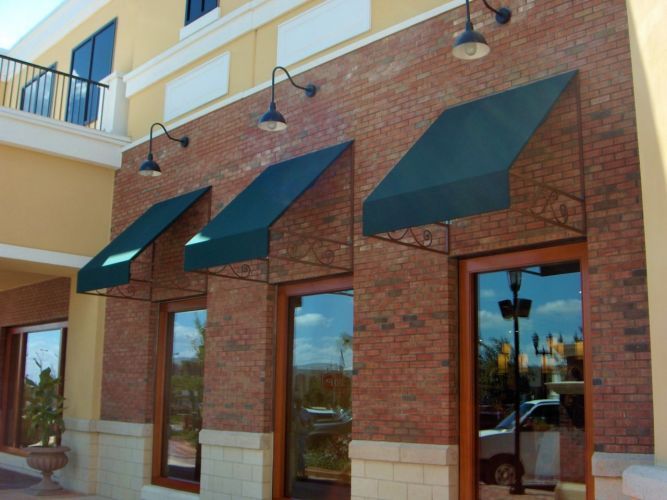 Brick building exterior with dark green awnings and large windows.