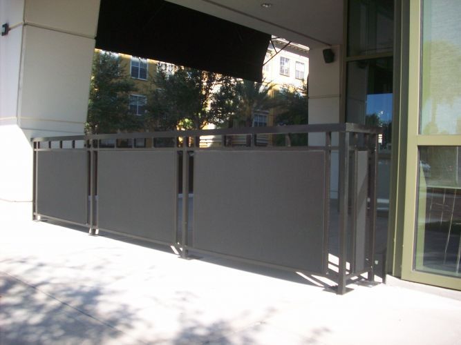 A dark gray fence outside of a building, possibly a patio with an awning.