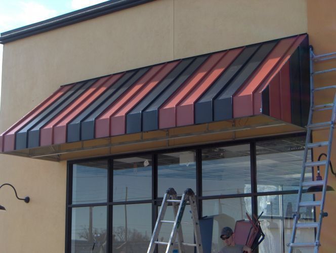 Red and black striped awning over a storefront window, with ladders and construction in front.